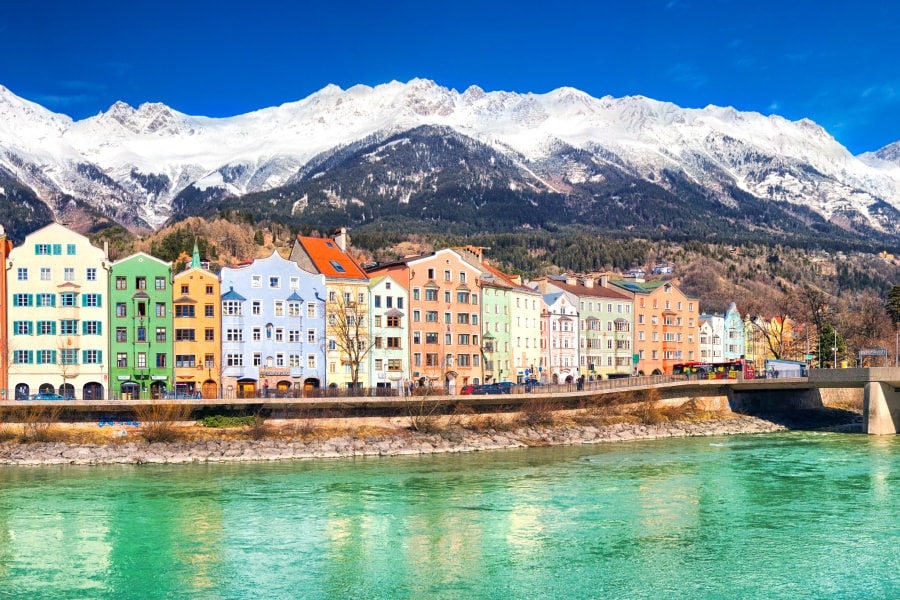 An Austrian city: colourful houses in front of a river and with mountains on the background