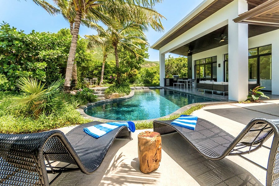 A modern-styled villa with a swimming pool among palm trees in St Kitts and Nevis